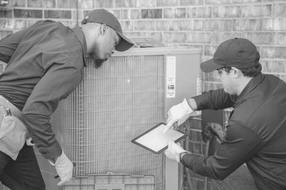 Two service technicians troubleshooting an issue with an air conditioning unit.