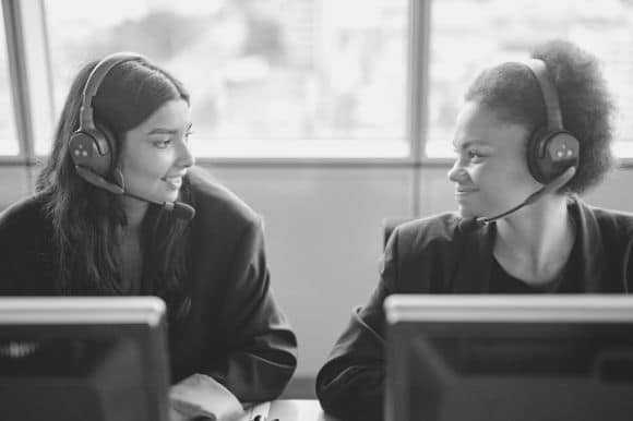 A telemarketer and her colleague having a brief conversation between client calls.