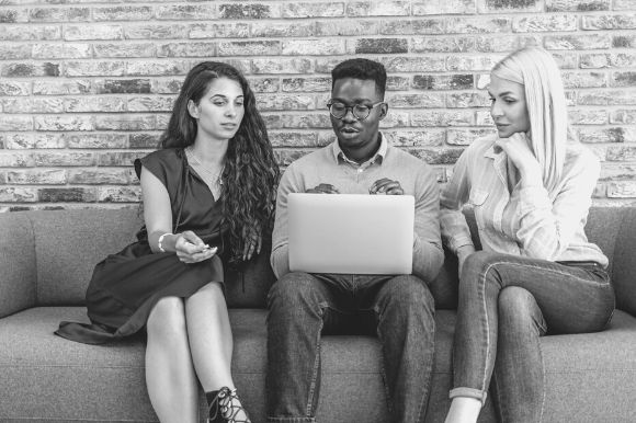 Recruiters sitting on a couch, reviewing the social media networks and other online information about candidates.