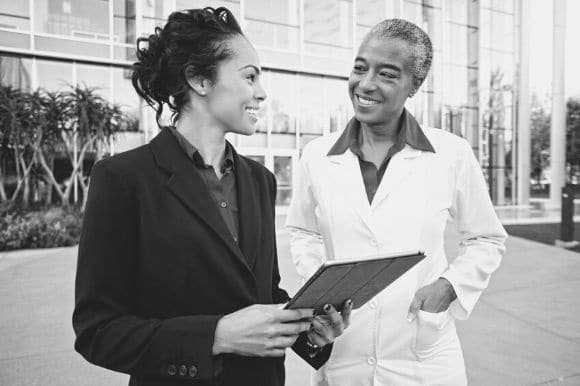 An administrative coordinator talking with a colleague outside the office building.