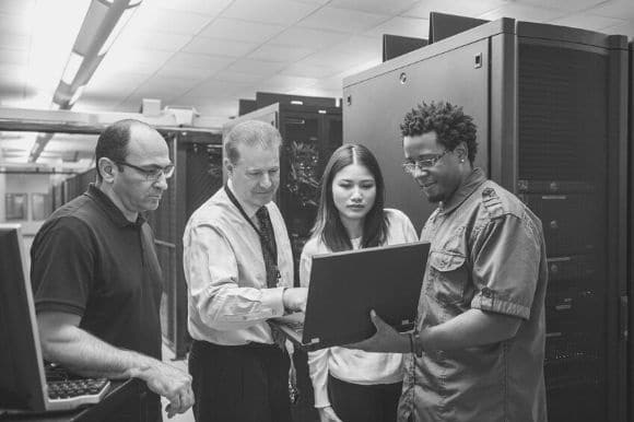 Compliance analyst discussing a project with three colleagues.