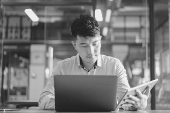 Database specialist working on computer and tablet at work