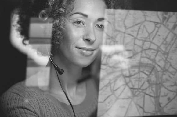 A dispatcher, wearing a headset, checks routes for her fleet of trucks.