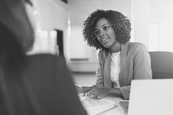 Hiring manager sitting at a desk, asking a job candidate great interview questions.