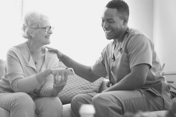 Home health aide looking at clients phone in her home.