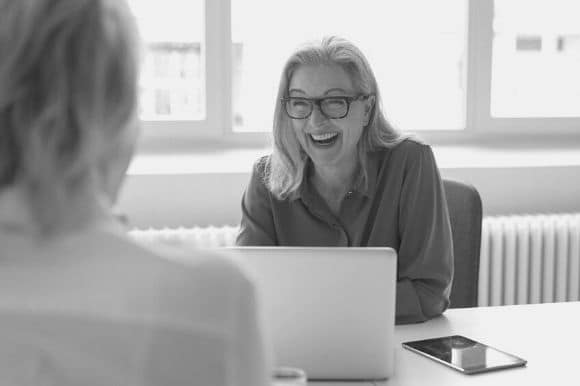 A hiring manager laughs with a job candidate as she asks icebreaker interview questions to lighten the mood.