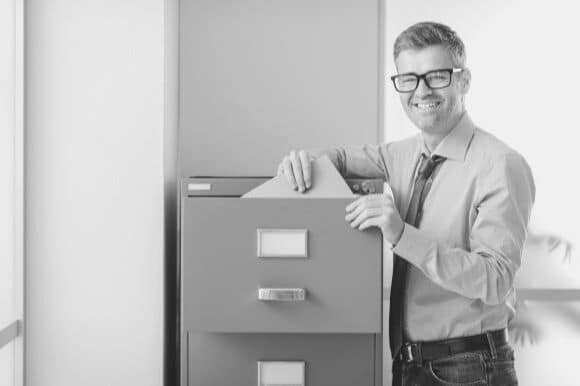 Medical records technician standing next to file cabinet in office