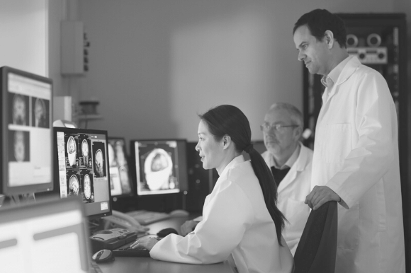 Neuroscientist with her colleagues, examining brain scans of a patient.