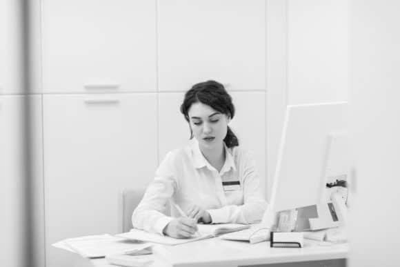 Office receptionist writing in an appointment book.