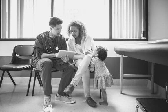 A patient care coordinator works closely with a new patient and her young daughter.