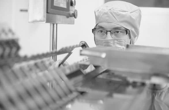 Pharmaceutical manufacturing technician working with machine at work