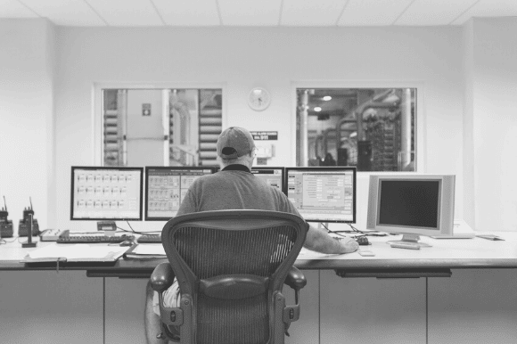 Security manager, sitting in front of several monitors in the surveillance room.