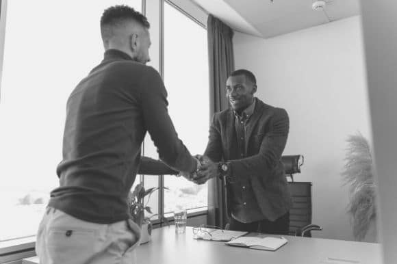 Knowing the best questions to ask interns can help you find the right fit, as this picture of a manager shaking the hand of a new interns illustrates.