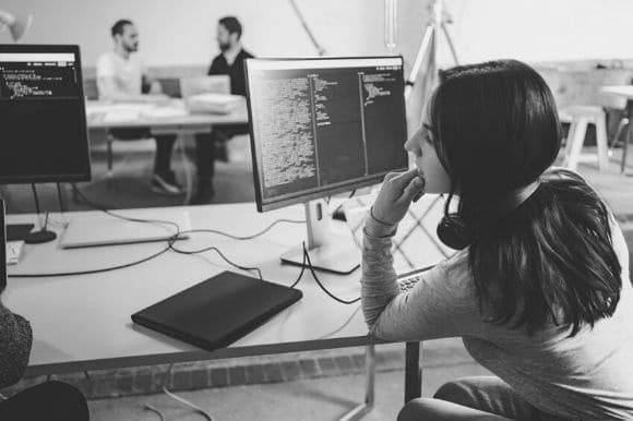 A web developer sitting at her desk and mulling over some code.