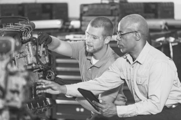 Maintenance supervisor showing employee how to inspect machinery