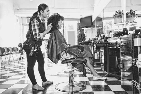 A cosmetologist works on a client's hair and makeup.