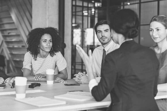 Managing partner of a law firm convening a meeting with her junior associates and other partners.