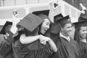 College graduate smiling and hugging her friend.