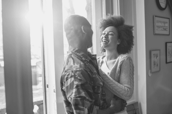 Military spouse embracing her husband, who is wearing camouflage fatigues.