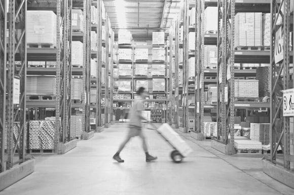 A warehouse logistics worker moves a package on a dolly.
