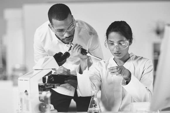 Two research assistants in a laboratory, examining a sample.