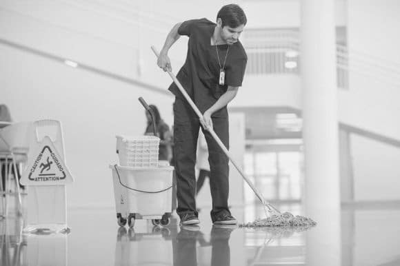 A cleaner mops the floors of a medical facility.