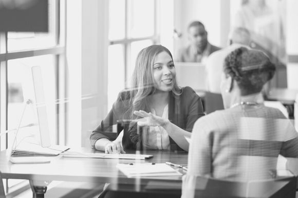 Investment banker at desk, meeting with a client.