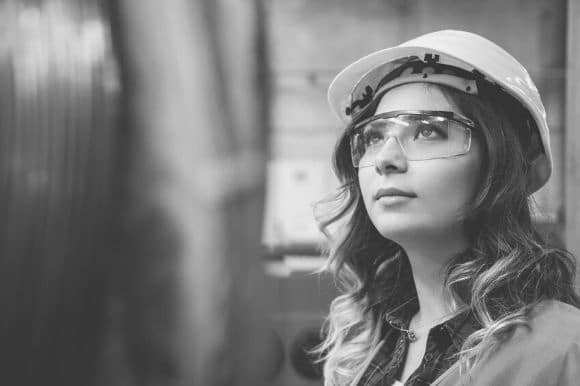 Process engineer in a hardhat checking a piece of equipment.