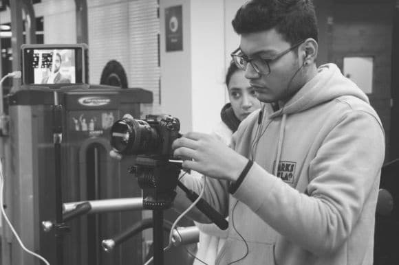 Production manager, setting up a camera on a tripod and making sure everything is ready for a photo shoot.