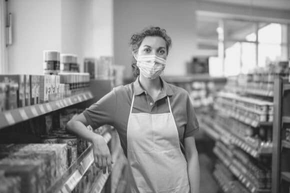 Grocery worker standing in aisle while wearing a mask