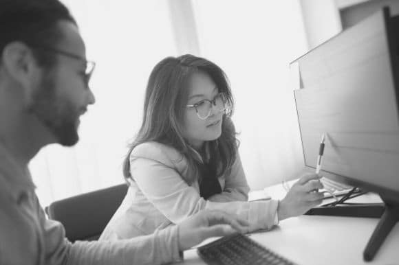 Two employees scrutinizing their recruitment data base as they implement data hygiene in their organization.