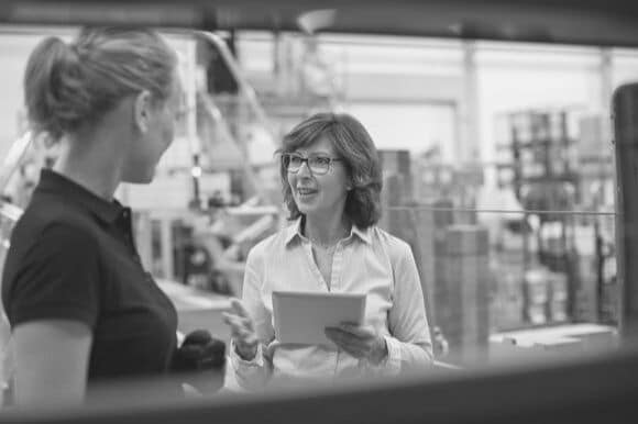 Warehouse operations manager talking with employee in storage area