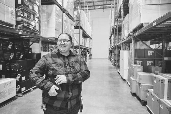 A warehouse worker, standing next to shelves.