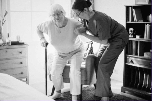 Caregiver helping a client up from a chair