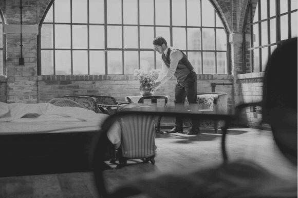 Butler putting flowers on table.