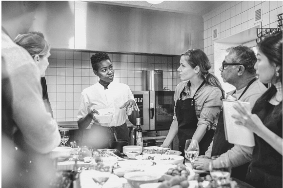 A chef meets with her staff in the kitchen.