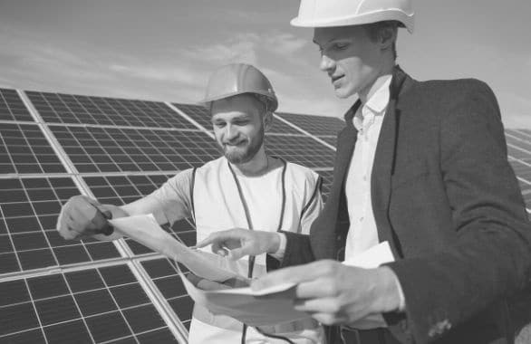 An electrician goes over plans with a building supervisor as they install a solar array.