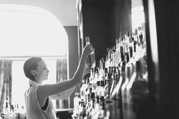 Barback placing bottles behind a bar