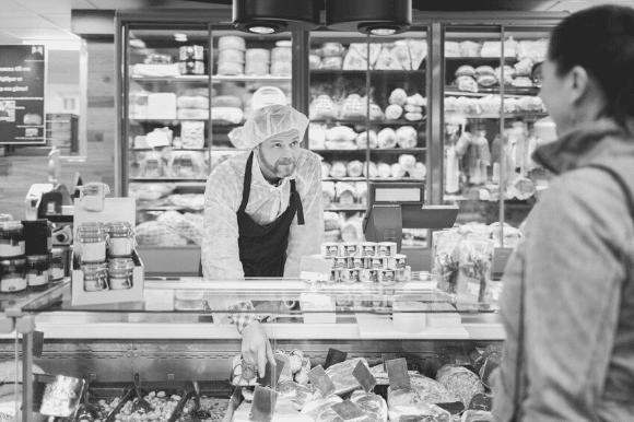 Deli clerk reaching into the cooler to get something for a customer.