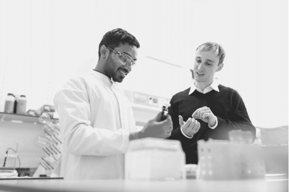 Environmental engineer testing substances in a laboratory, talking to a colleague.