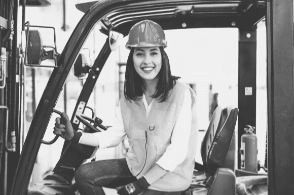 Worker sitting on forklift and smiling at camera