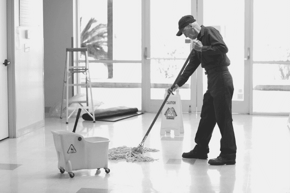 Janitor with mop and bucket, cleaning an office floor.