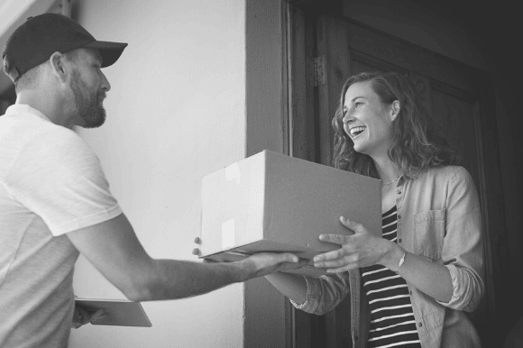 Mail carrier delivering a box to a happy customer.