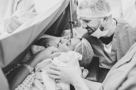 Neonatal nurse comforting mom after she delivers her baby.
