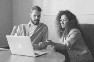 Hiring managers, sitting down at a computer, reviewing applications with the help of an applicant tracking system.