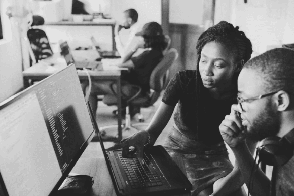 Tech support professional helping her coworker with a problem.