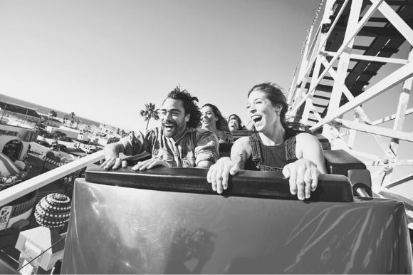 Two people riding a rollercoaster at a theme park, part of the leisure and hospitality industry.