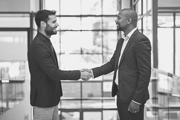 Two men shaking hands, after one of them offers the other a new position at the company.