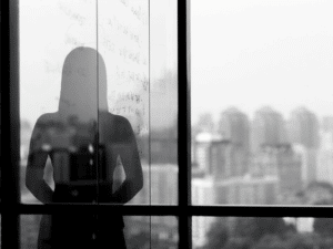 Silhouette shadow of woman looking at city from office. Ghosting
