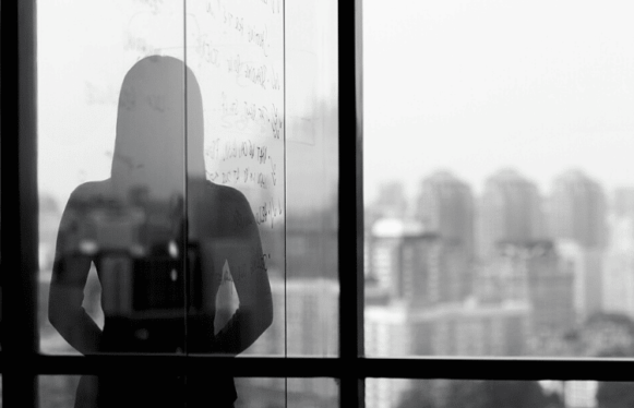 Silhouette shadow of woman looking at city from office